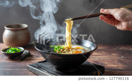 用筷子夾起熱氣騰騰的豬骨拉麵 127790116
