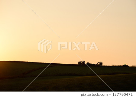 Sunset-colored fields and tractors Sunset-colored fields and tractors 127790471