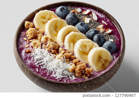 Morning shake. Colorful acai bowl with banana slices, coconut flakes and granola on a white background.  Healthy and Wellness Breakfast for luxury resorts. 127790907