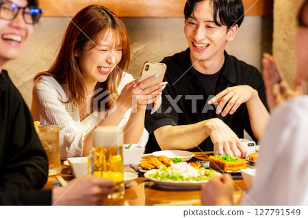 Men and women looking at smartphones at an izakaya Men and women looking at smartphones at an izakaya 127791549