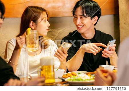 Men and women looking at smartphones at an izakaya 127791550