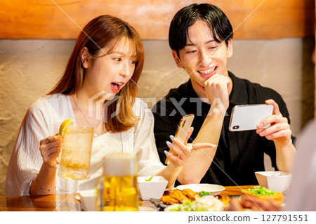 Men and women looking at smartphones at an izakaya Men and women looking at smartphones at an izakaya 127791551