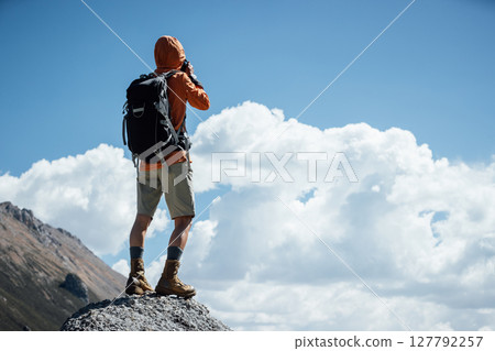 Woman photographer taking picture on high altitude mountain top 127792257