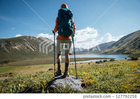Woman backpacker hiking on high altitude mountain top,with a lake in the distance Woman backpacker hiking on high altitude mountain top,with a lake in the distance 127792258