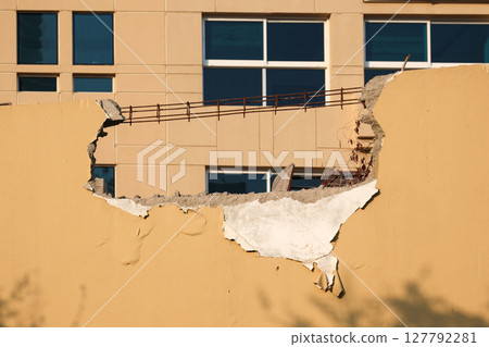 Large hole in the fence of the building 127792281