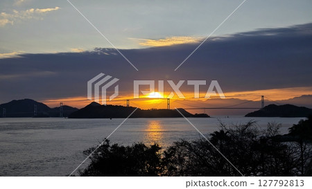 The sun rising over the Shimanami Kaido and the silhouette of a bridge The sun rising over the Shimanami Kaido and the silhouette of a bridge 127792813