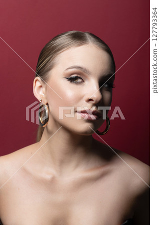 Beautiful woman portrait with classic hairstyle, naked shoulders and round golden earring 127793364