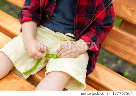 Little child eats fresh green peas which gives his mother. Selective focus, defocus. Little child eats fresh green peas which gives his mother. Selective focus, defocus. 127793504