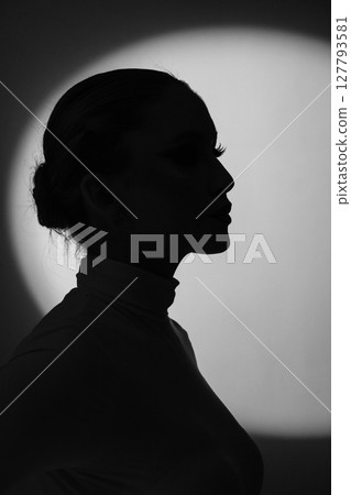 Woman profile black silhouette portrait in bright illuminated round light background Woman profile black silhouette portrait in bright illuminated round light background 127793581