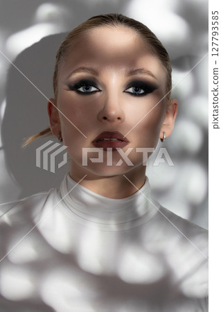 Beautiful woman with fancy make-up standing in shadow and looking at camera 127793585