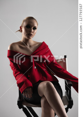 Beautiful woman with red jacket and mini shirt sitting in high chair 127793587