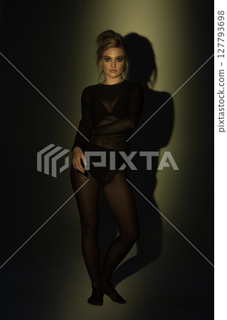 Beautiful woman with tight black clothes studio background 127793698