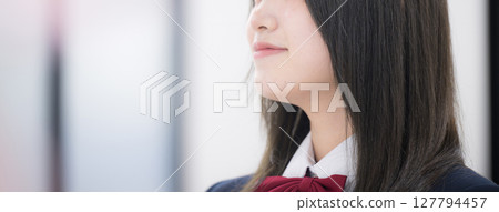 Close-up of a smiling high school girl in profile at school or cram school, no face banner 127794457