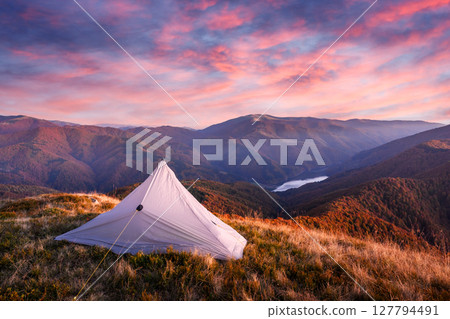 Grey tent against the backdrop of an incredible mountains lake 127794491