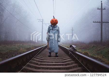 Terrifying person in carved pumpkin mask with axe Terrifying person in carved pumpkin mask with axe 127794524