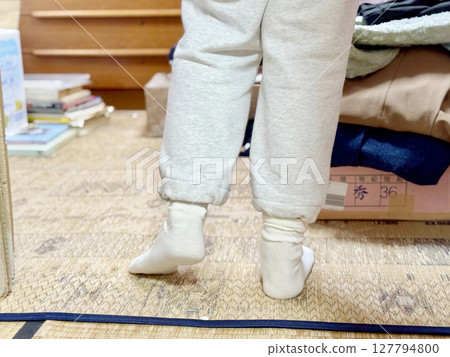 The back of a person wearing sweatpants standing in a messy room 127794800