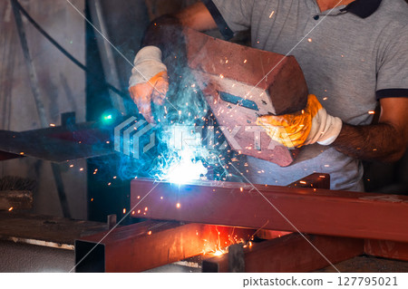 Metal worker is welding metals with protection of him self 127795021