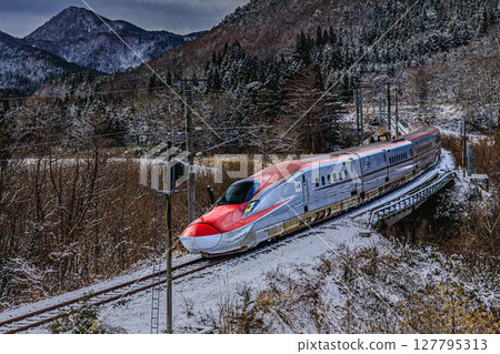Akita Shinkansen Komachi running through the snowy fields 127795313