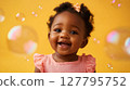 Delighted African American baby girl with pink bow smiles widely surrounded by floating soap bubbles against vibrant yellow background. Perfect for themes of infancy, joy and playfulness 127795752