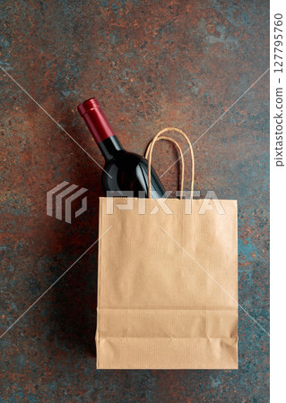 Bottle of red wine in a paper bag on a rusty background. Bottle of red wine in a paper bag on a rusty background. 127795760