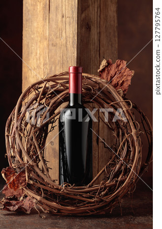 Bottle of red wine and dried grapevine wreath. 127795764