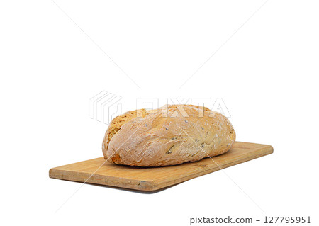 A whole loaf of baked homemade bread lies on a wooden cutting board made of bamboo wood, isolated on a white background with a clipped path with copy space. Blank for artwork, bakery theme 127795951