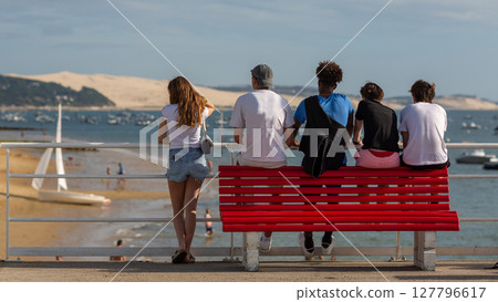 people sitting on a bench looking at the sea people sitting on a bench looking at the sea 127796617