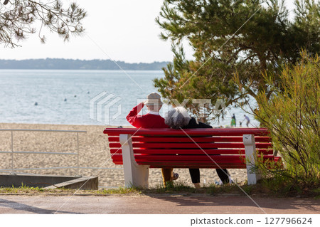 senior couple sitting on a bench looking at the sea 127796624