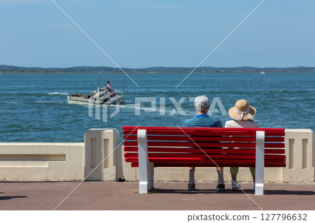 senior couple sitting on a bench looking at the sea senior couple sitting on a bench looking at the sea 127796632