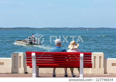 senior couple sitting on a bench looking at the sea 127796634