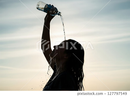 Athletic Woman Pouring Water Over Head During Intense Outdoor Training Session Athletic Woman Pouring Water Over Head During Intense Outdoor Training Session 127797549
