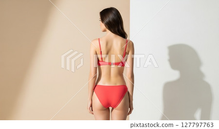 Elegant Red Bikini Fashion Model Poses Against Minimalist Studio Background 127797763