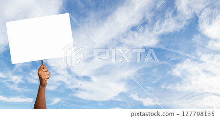 Hand holding a blank sign against a blue sky with fluffy clouds during daylight Hand holding a blank sign against a blue sky with fluffy clouds during daylight 127798135