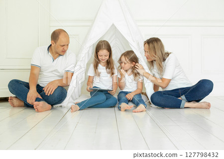 Adorable family using tablet gadget at home. Father, mother and two daughter 127798432