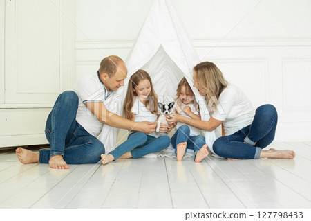 Smiling family having fun with puppy dog pet at home Smiling family having fun with puppy dog pet at home 127798433
