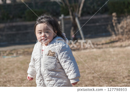[A one-year-old child playing on the grass at Sagamihara Municipal Asamizo Park] 127798933