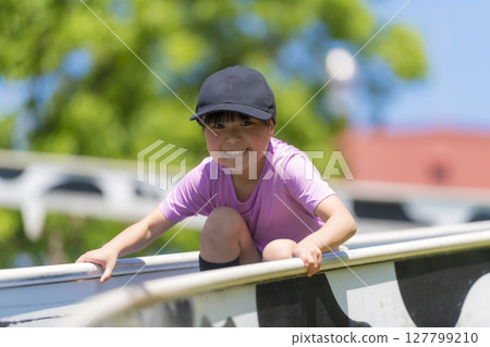 微笑的小學女孩在公園玩滑梯 127799210