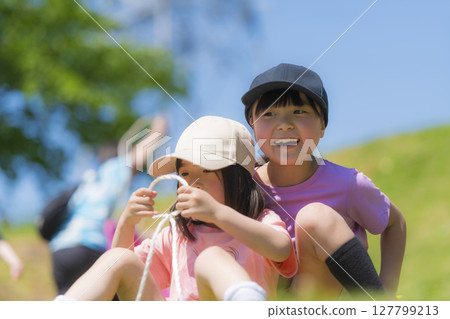Children sledding down the grass 127799213