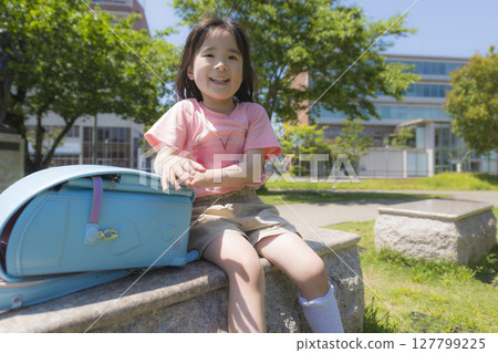 背著淺藍色書包在公園休息的小學生 127799225