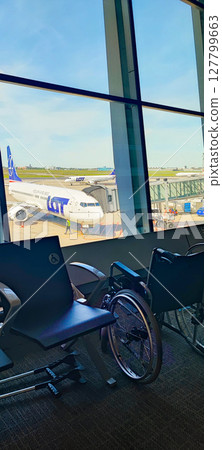 View from the airport terminal with a wheelchair and crutches in the foreground. Concept of inclusiveness and assistance at the airport for disabled people, pensioners View from the airport terminal with a wheelchair and crutches in the foreground. Concept of inclusiveness and assistance at the airport for disabled people, pensioners 127799663