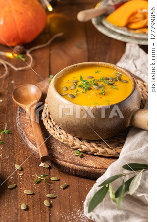 Tasty pumpkin cream soup with organic herbs and pumpkin seeds in vintage ceramic bowl Tasty pumpkin cream soup with organic herbs and pumpkin seeds in vintage ceramic bowl 127799856