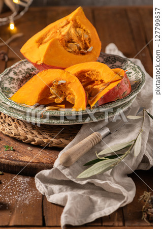 Sliced hokkaido pumpkin on a wooden board. Autumn cozy cooking concept Sliced hokkaido pumpkin on a wooden board. Autumn cozy cooking concept 127799857