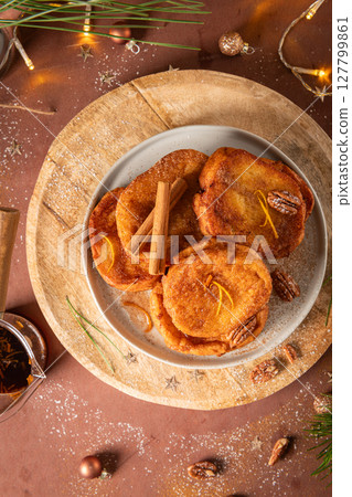 Traditional Christmas french toast or rabanadas with sugar syrup, cinnamon and pecan nuts on a rustic kitchen counter at Christmas time. Traditional Christmas french toast or rabanadas with sugar syrup, cinnamon and pecan nuts on a rustic kitchen counter at Christmas time. 127799861