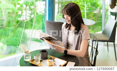 A woman reading a magazine at a cafe A woman reading a magazine at a cafe 127800087