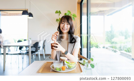 微笑的女人在咖啡館吃午餐 127800093