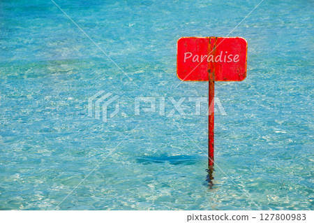 turquoise tropical sea with red sign saying Paradise 127800983