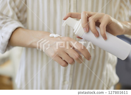 Close up of woman applying moisturizing natural cream on her hand for skin care and protection. 127801611