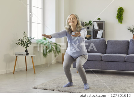 Squat exercise of senior woman training at home,old happy lady with arms stretching forward 127801613