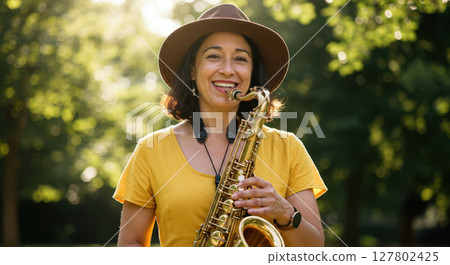 Smiling Woman Playing Saxophone Outdoors in Sunny Park 127802425