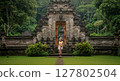 Balinese Woman in Traditional Attire at Temple Entrance in Ubud, Indonesia 127802504